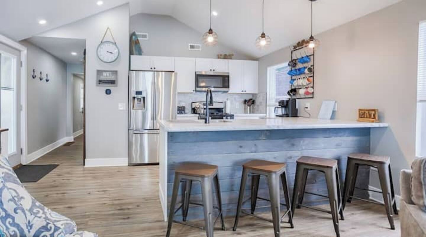 A modern kitchen with a central island, stainless steel appliances, and bar stools.