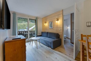 A room with a sofa, a small table, a TV, and a wooden cabinet.