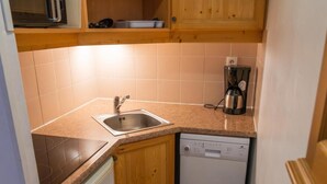 Une cuisine de taille réduite équipée d’un évier, d’un lave-vaisselle et d’une machine à café.