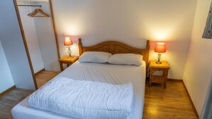 Un lit bien fait, avec une literie blanche, deux lampes de chevet et une tête de lit en bois.