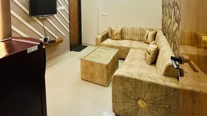 A modern living room with a sectional sofa, a coffee table, a flat-screen TV, and a ceiling fan.