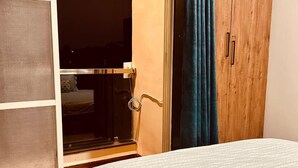 A bedroom with a bed, a wardrobe, and a window with curtains.