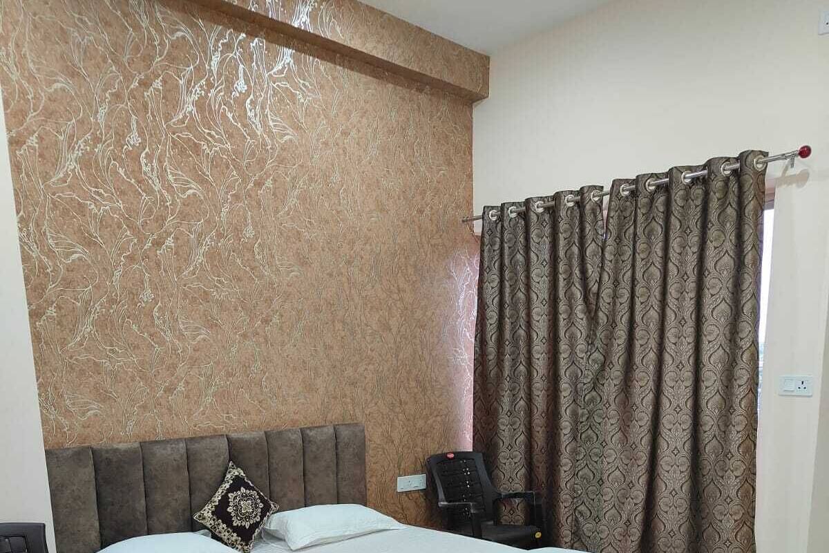 Un dormitorio con una cama grande, cabecera, mesita de noche, una silla y una cortina.