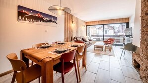 Ein moderner Essbereich mit einem Holztisch, gedeckt für sechs Personen, roten Stühlen und einem großen Fenster mit Blick auf die Stadt.