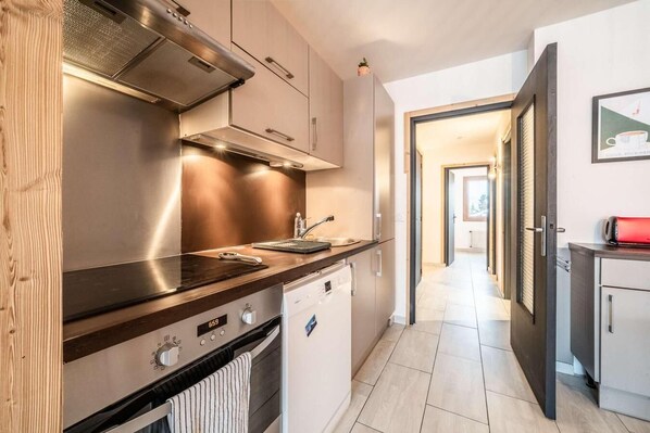 A modern kitchen with stainless steel appliances, a wooden countertop, and a view into the adjacent living area.