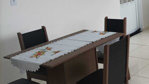 A dining table with a lace tablecloth, four wooden chairs, and a white door with a metal grill.