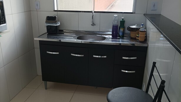 A kitchen with a sink, two chairs, and a window.