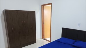 A bedroom with a large wardrobe, a bed with blue bedding, and a wooden door.