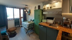 A compact kitchen with a dining area, a green cabinet, and a coffee machine.