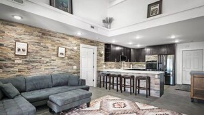 Una cocina moderna con armarios oscuros, una isla central con taburetes y una pared de acento de piedra.