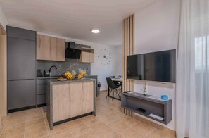 A modern kitchen with a built-in island, a dining area with a TV, and a large window.