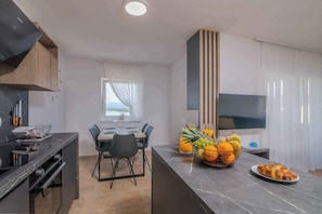 Une cuisine moderne avec un coin repas, un four encastré et une grande fenêtre avec des rideaux.