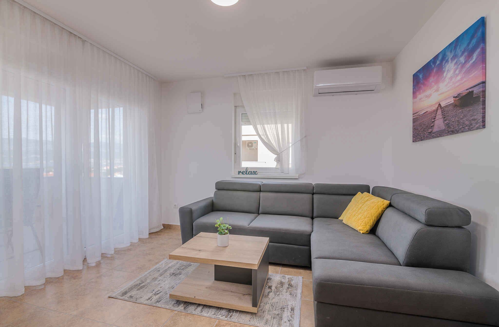 A modern living room with a grey sectional sofa, a wooden coffee table, and a yellow pillow.
