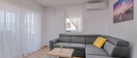 A modern living room with a grey sectional sofa, a wooden coffee table, and a yellow pillow.