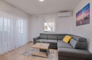 Un soggiorno moderno con un divano modulare grigio, un tavolino in legno e un cuscino giallo.