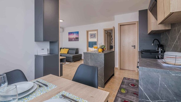 A modern apartment with a dining area, kitchen, and living space. - Holiday apartment Apartment with heated pool and sea view (Klimno)