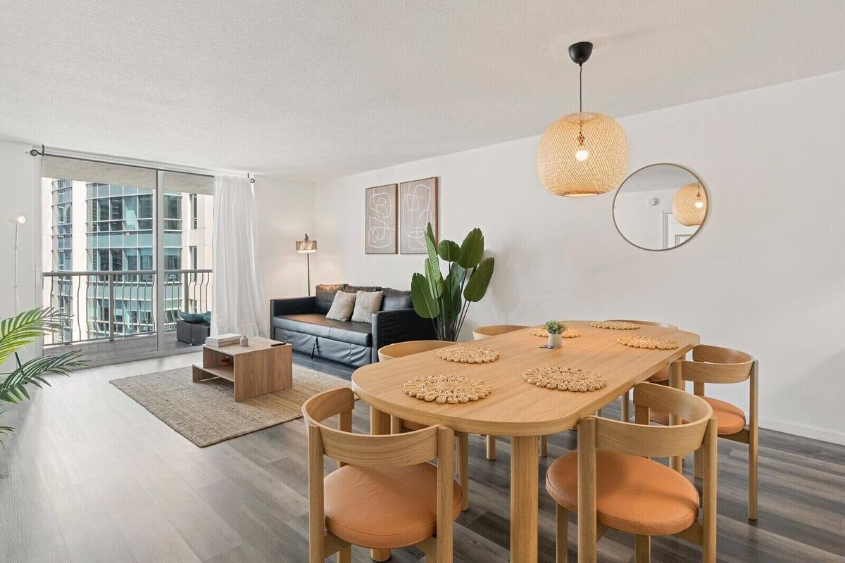 A modern living room with a dining area, large windows, and a view of the cityscape.