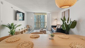 Ein modernes Wohnzimmer mit Esstisch, großen Fenstern und einer Pendelleuchte.