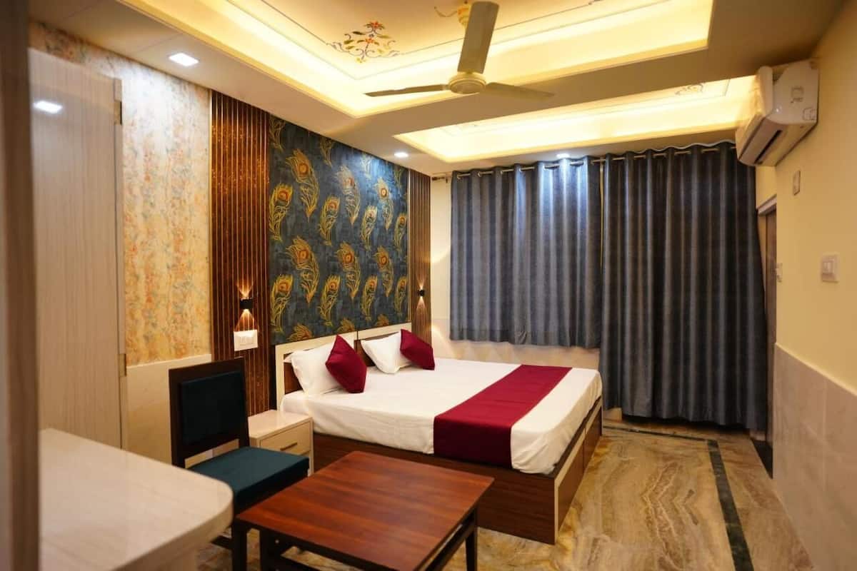 A hotel room with a bed, bedside table, chair, and a desk.