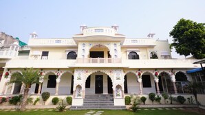 A two-story building with a central entrance, ornate arches, and a balcony. - Aashirwad Haveli (Sawai Madhopur)