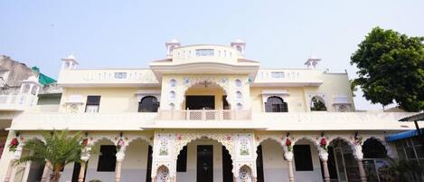 A two-story building with a central entrance, ornate arches, and a balcony.