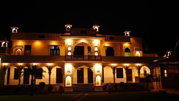 A large, illuminated building with multiple arches and a central balcony, likely a hotel or historic building. - Aashirwad Haveli (Sawai Madhopur)