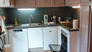 A compact kitchen with white cabinets, a built-in dishwasher, a coffee maker, and a toaster. - House and garden for 6 people near lakes and hiking trails (Luc)