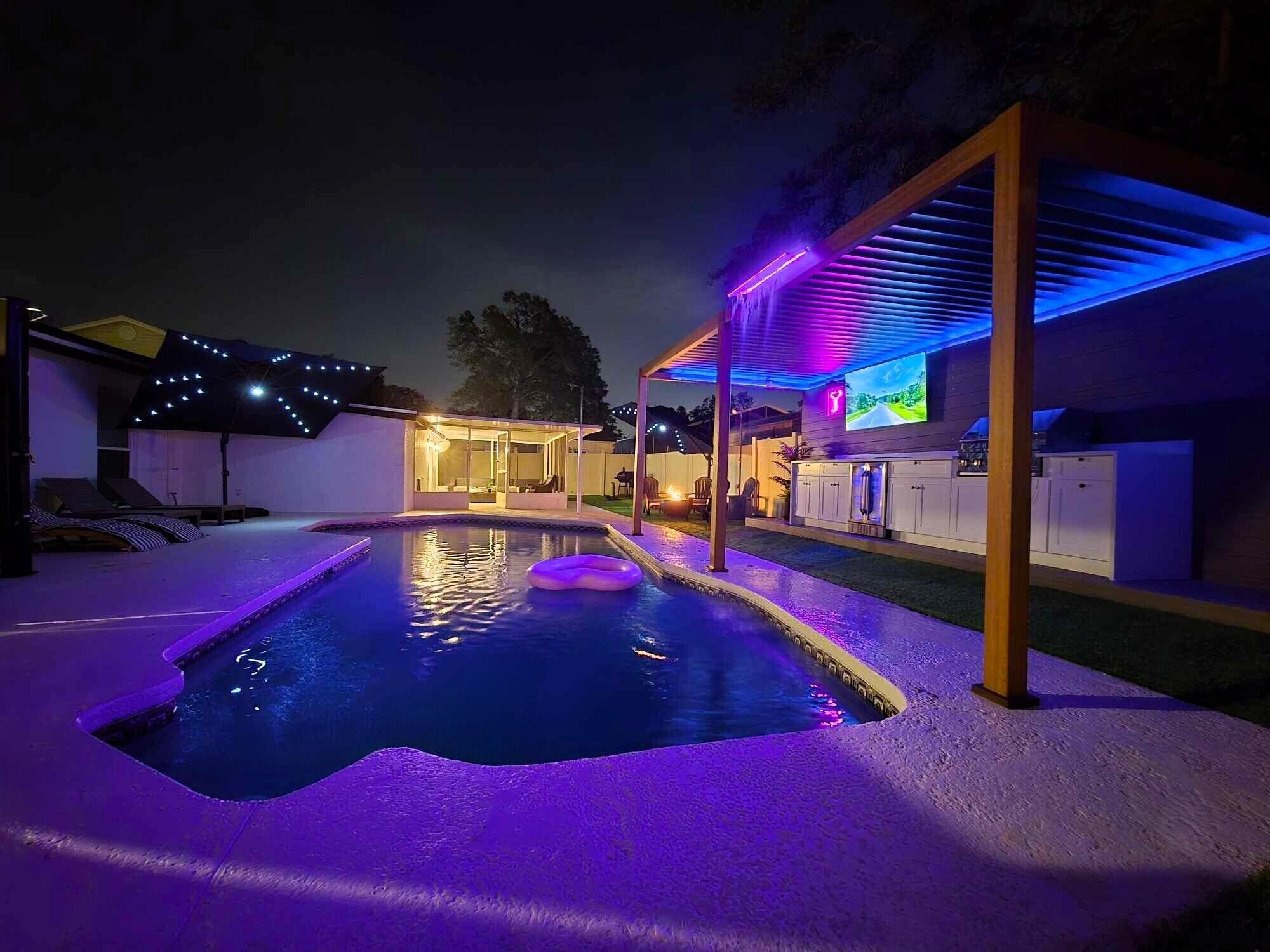 Une piscine dotée d’une zone couverte et d’une structure illuminée par des néons.