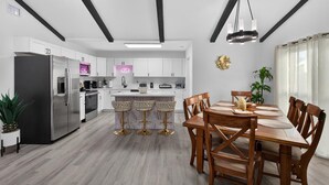 A modern kitchen with white cabinets, a stainless steel refrigerator, and a central island with bar stools.