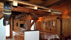 Interior de madera con área de cocina, mesa y sillas.