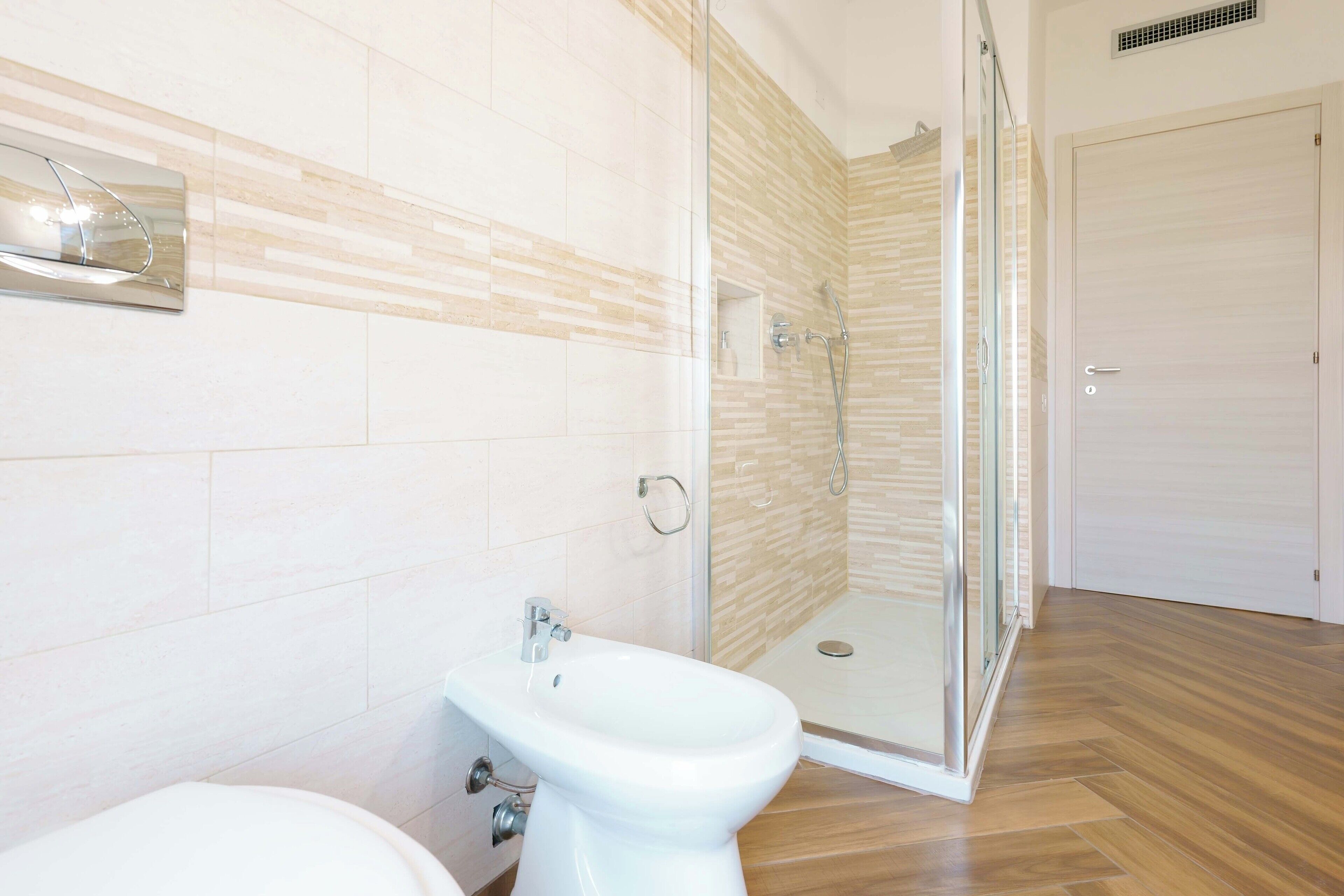 Une salle de bain moderne avec une douche à l’italienne en verre, un lavabo blanc et des toilettes.