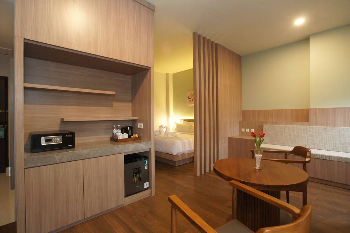 Quarto de hotel compacto com cozinha compacta, cama, área de estar e uma pequena mesa.