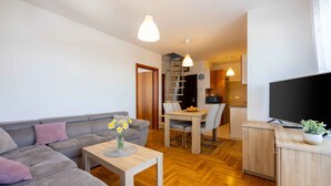 Un salon moderne avec un canapé gris, une table basse en bois et un téléviseur posé sur un meuble en bois.