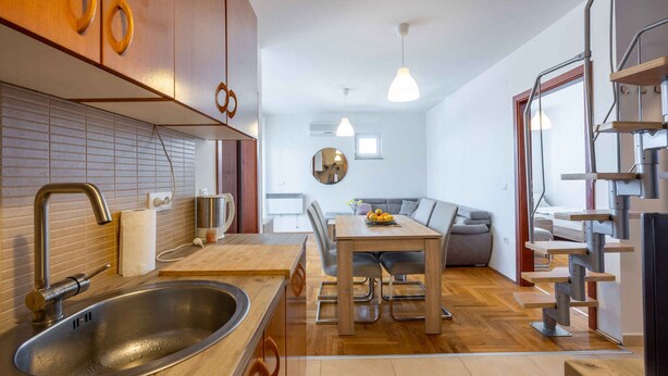 Une cuisine moderne équipée d’un évier, de meubles en bois et d’un coin repas avec une table et des chaises.