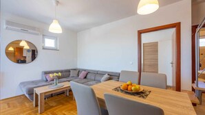 Un salon moderne avec un canapé gris, une table à manger en bois et un miroir rond.