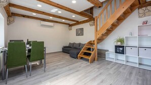 Ein moderner Wohnraum mit Essbereich, Sofa, Treppe und integrierten Regalen.