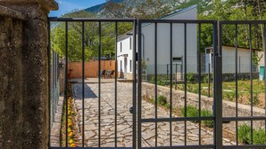 Ein Innenhof mit Steinboden, einem Metallgitter und einem weißen Gebäude mit schrägem Dach.