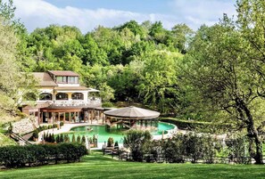 Ein großes Haus mit Pool, Laube und gepflegtem Garten.