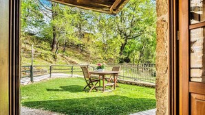 A patio with a table and chairs, surrounded by a metal fence and a grassy area with trees. - Holiday apartment with air conditioning and pool (Sorano)