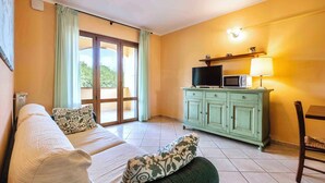 A room with a bed, a TV, a microwave, and a cabinet. - Holiday apartment with air conditioning and pool (Sorano)