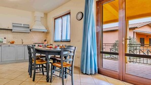 Una cocina con una mesa de comedor y sillas, un reloj en la pared y vistas al balcón exterior.