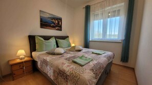 Une chambre à coucher avec un lit, une table de chevet, une lampe et un tableau au mur.