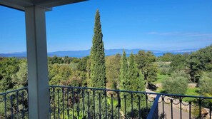 En balkon med udsigt over et bjergrigt landskab og et vandområde.