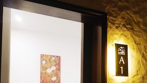 Une chambre d’hôtel avec un lit, un tableau accroché au mur et une pancarte indiquant le numéro de chambre : A1.