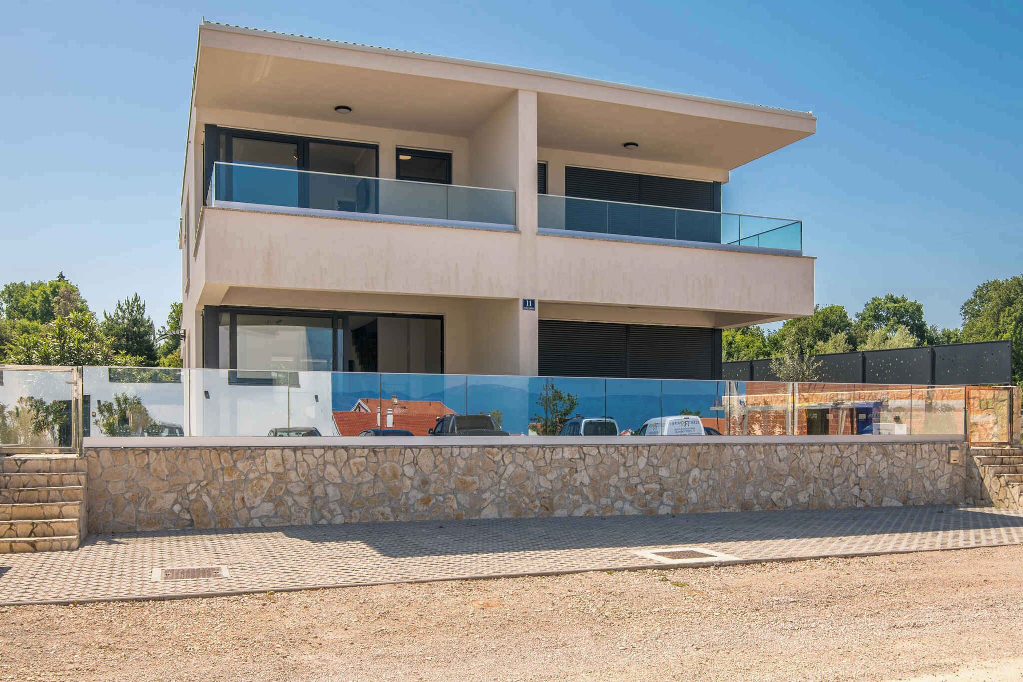 Un edificio moderno de dos pisos con fachada de piedra, ventanas grandes y un balcón.