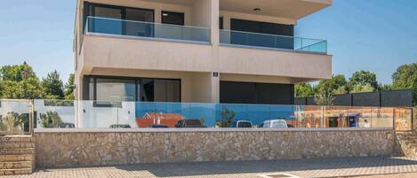Un edificio moderno de dos pisos con fachada de piedra, ventanas grandes y un balcón.