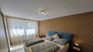 A modern bedroom with a large bed, a desk, and a chair. - Holiday apartment with terrace and air conditioning (Bük)