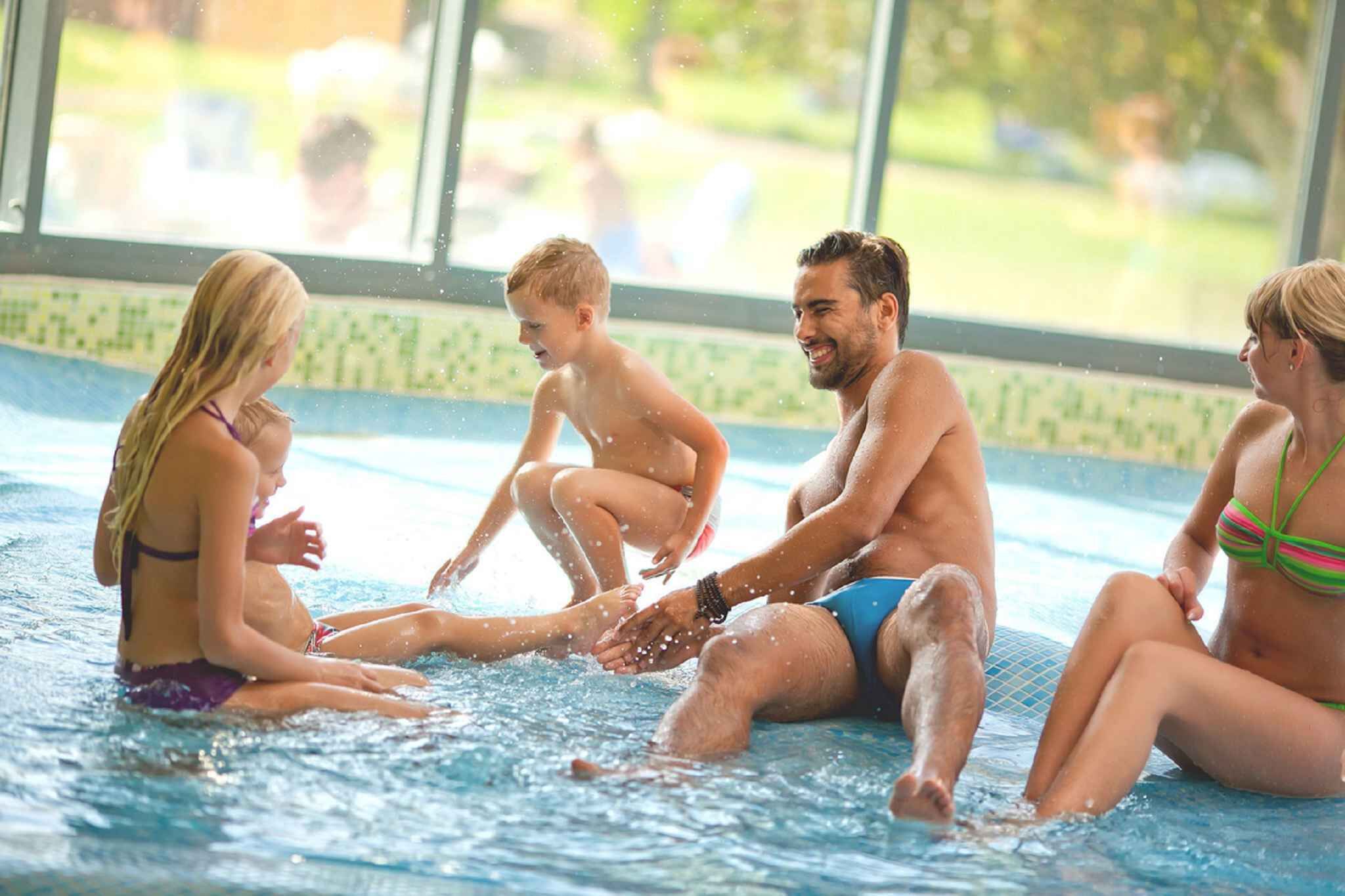 Ein Schwimmbecken mit Personen, die darum sitzen und stehen.