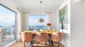 A dining area with a large window, a table set for four, and a view of the city. - Baltic Sea vacation apartment "Meeresflüstern" with sea view, sauna and close to the beach (Olpenitz)