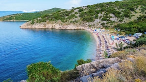 A coastal beach with clear blue waters, rocky cliffs, and lush greenery. - Holiday apartment with balcony (Njivice)